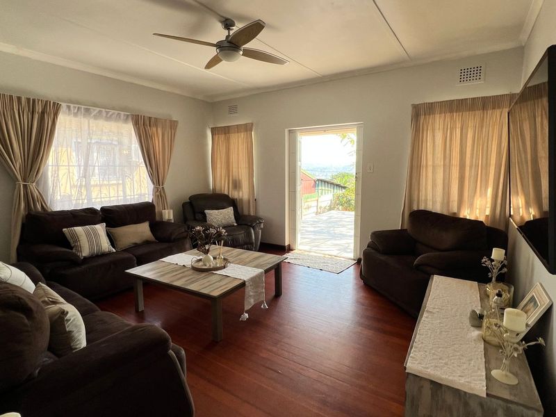 A comfortable living room featuring warm hardwood flooring, a ceiling fan, and direct access to an outdoor patio area through a glass door.