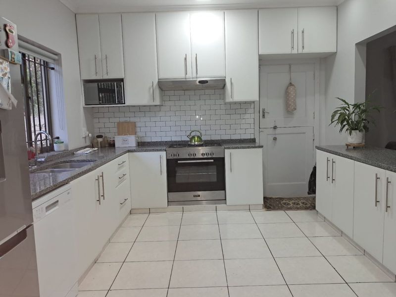 A well-maintained kitchen featuring white cabinetry, granite countertops, subway tile backsplash, and integrated stainless steel appliances.