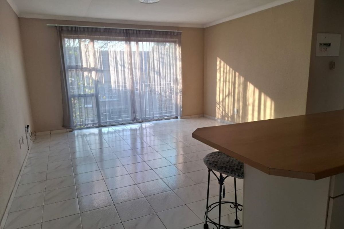 An open-plan living area featuring tiled flooring, a breakfast bar, and a large sliding glass door providing access to the exterior.