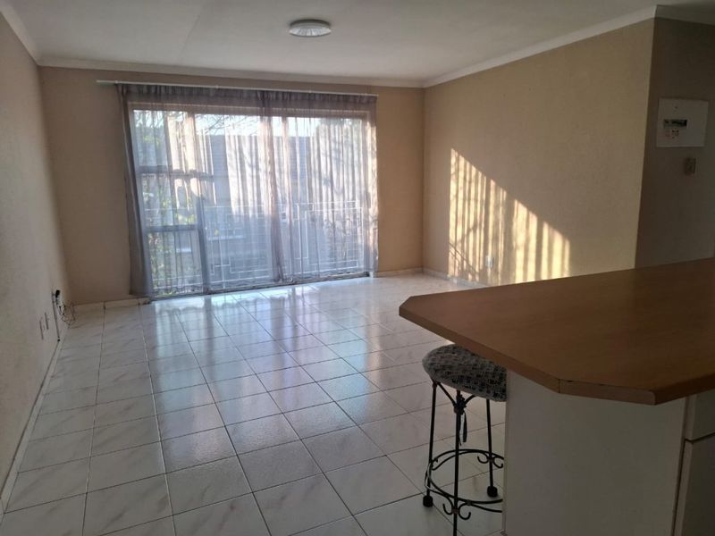 An open-plan living area featuring tiled flooring, a breakfast bar, and a large sliding glass door providing access to the exterior.