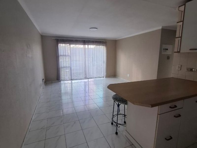 Open-plan living and kitchen area featuring tiled flooring, a breakfast island with built-in cabinetry, and a sliding glass door leading to the exterior.