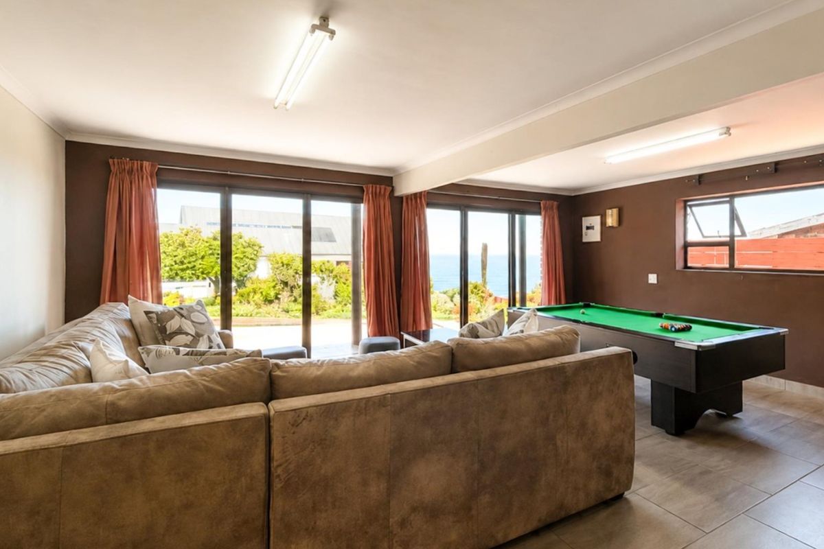 Spacious living area featuring large sliding glass doors with garden and sea views, tiled flooring, and neutral wall finishes.