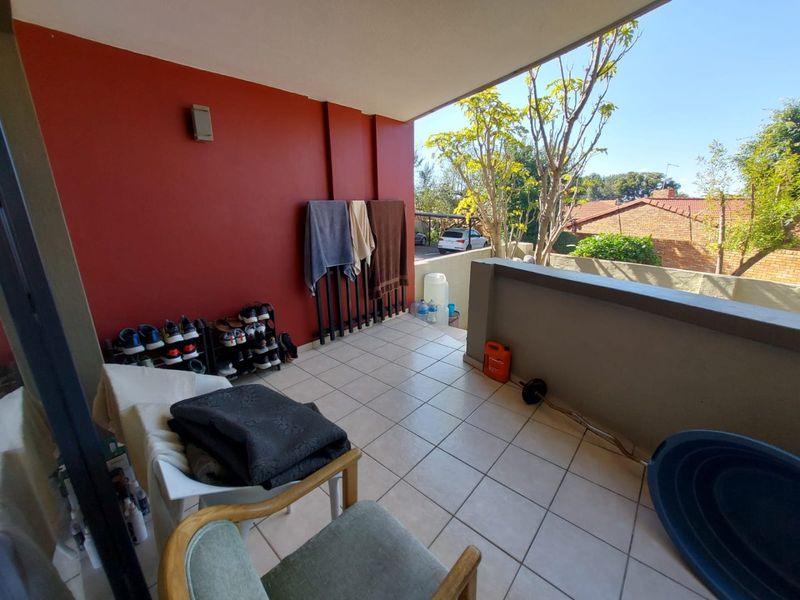A covered balcony featuring tiled flooring and a masonry balustrade, offering an outdoor space with views of the surrounding neighborhood.