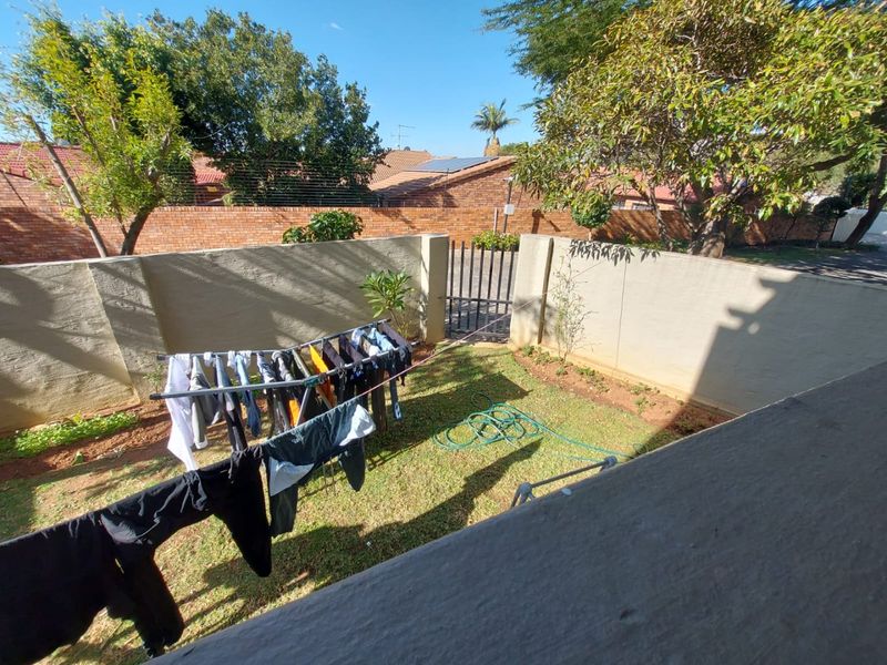 A private rear garden area featuring a lawn, perimeter boundary walls, and a secure metal access gate.