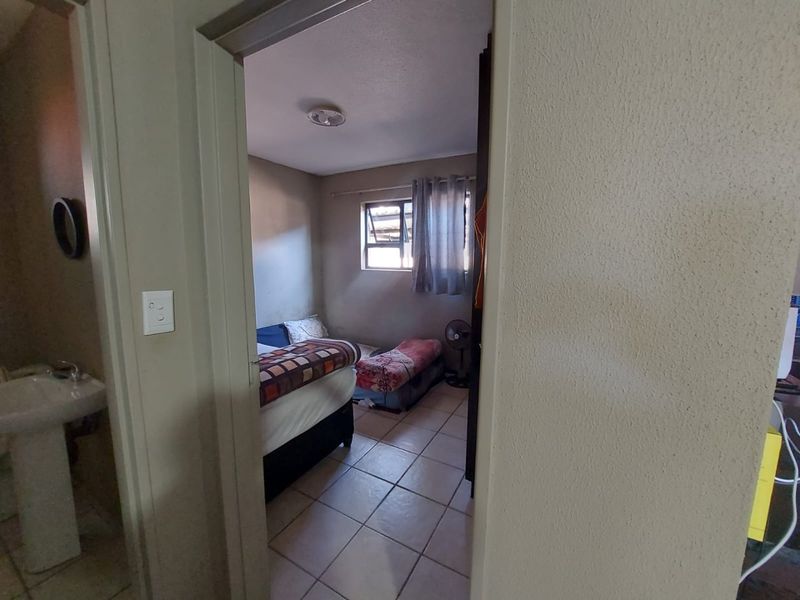 A compact bedroom featuring tiled flooring and a top-hung window, providing a functional sleeping space with built-in storage.
