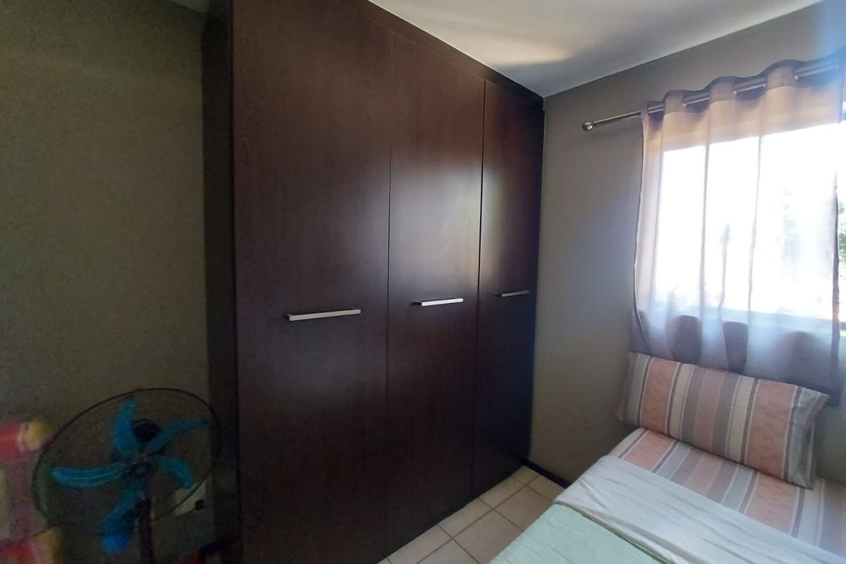 A bedroom featuring a dark wood built-in wardrobe and tiled flooring, providing functional storage space within the room.