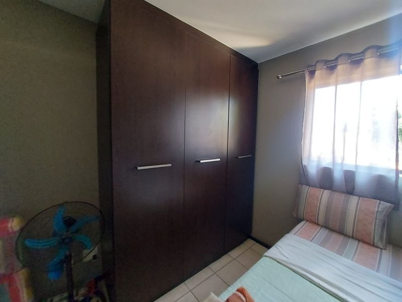 A bedroom featuring a dark wood built-in wardrobe and tiled flooring, providing functional storage space within the room.