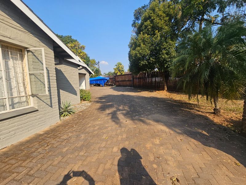 A view of the property's paved driveway and front facade, featuring a brick exterior and timber boundary fencing.