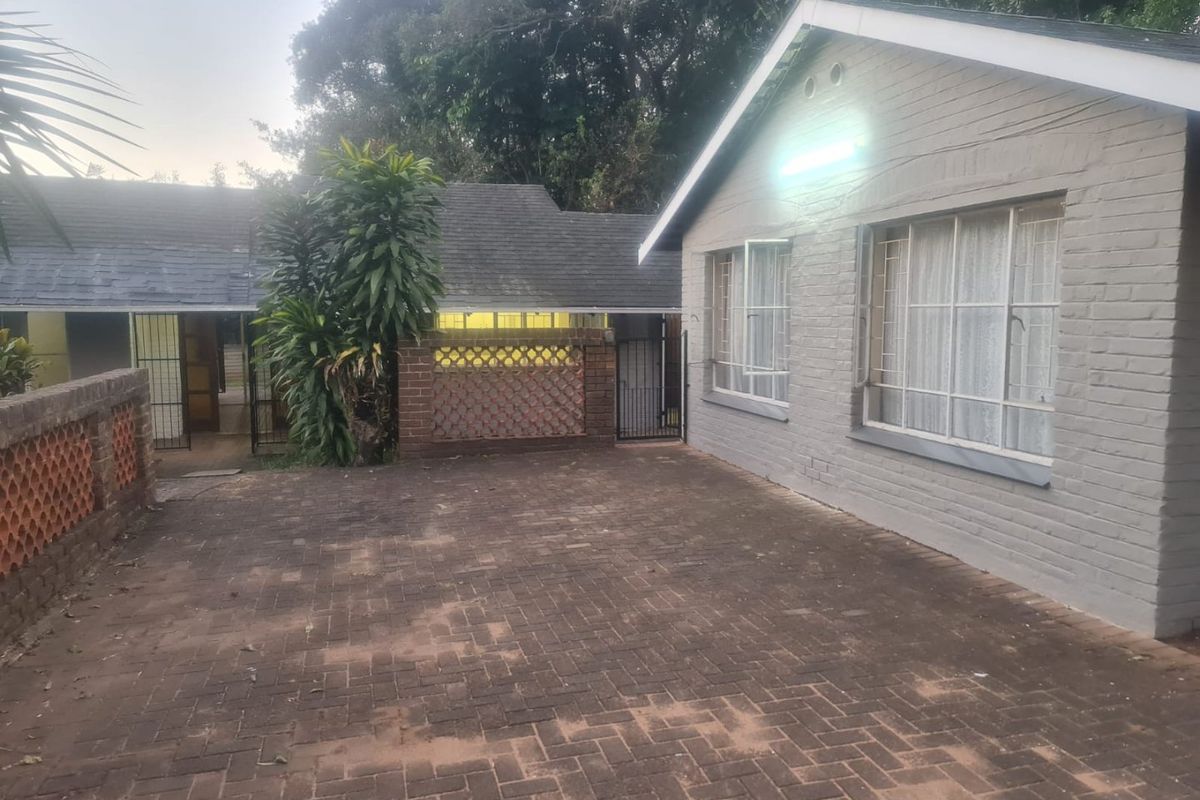 Rear exterior view of the property featuring a brick paved courtyard, painted brick walls, and secure gated access.