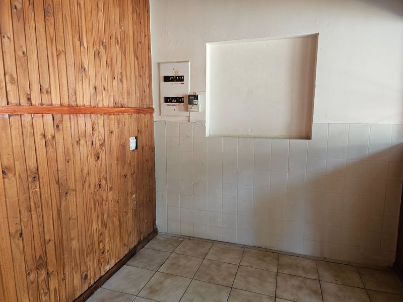 Utility area featuring timber wall paneling, tiled flooring, and a wall-mounted electrical distribution board.