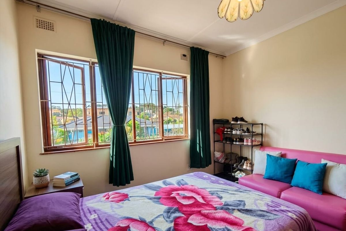 A bedroom featuring large windows with security bars, providing natural light and views of the surrounding neighborhood.