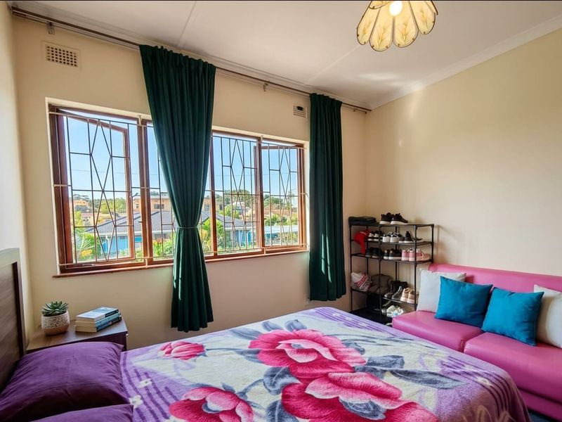 A bedroom featuring large windows with security bars, providing natural light and views of the surrounding neighborhood.