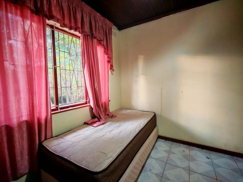 A bedroom featuring tiled flooring, a timber ceiling, and security bars on the window. The room requires cosmetic updates to the walls and flooring.