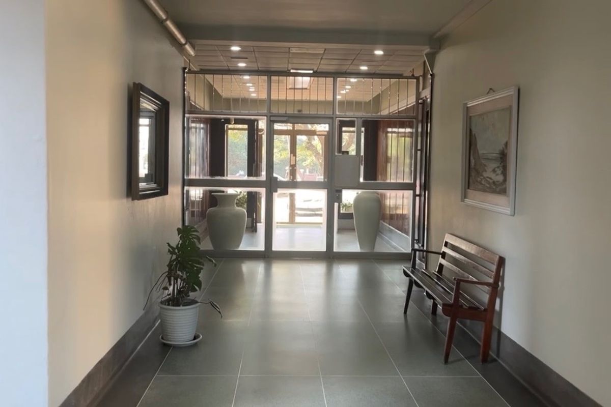 A bright and welcoming apartment entrance hall featuring tiled flooring, recessed ceiling lights, and a secure glass-panelled entrance door.