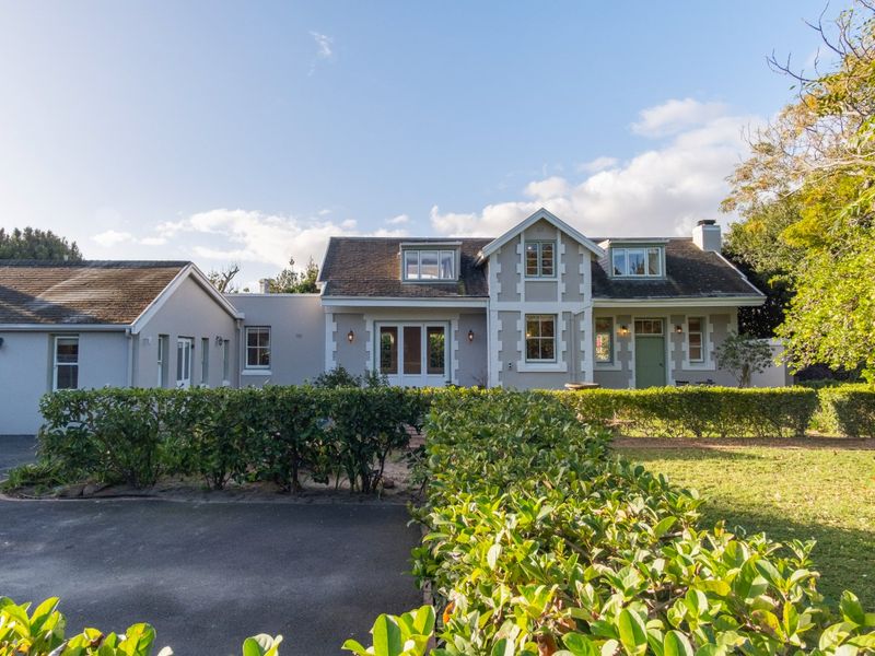 A charming double-story residence featuring a pitched roof, dormer windows, and a well-maintained front garden with a paved driveway.