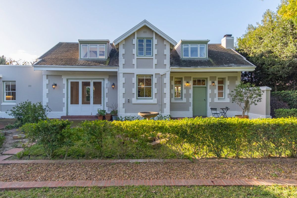 A charming rear elevation of a house featuring a pitched roof with dormer windows, a chimney, and a well-maintained garden with a brick-paved path.