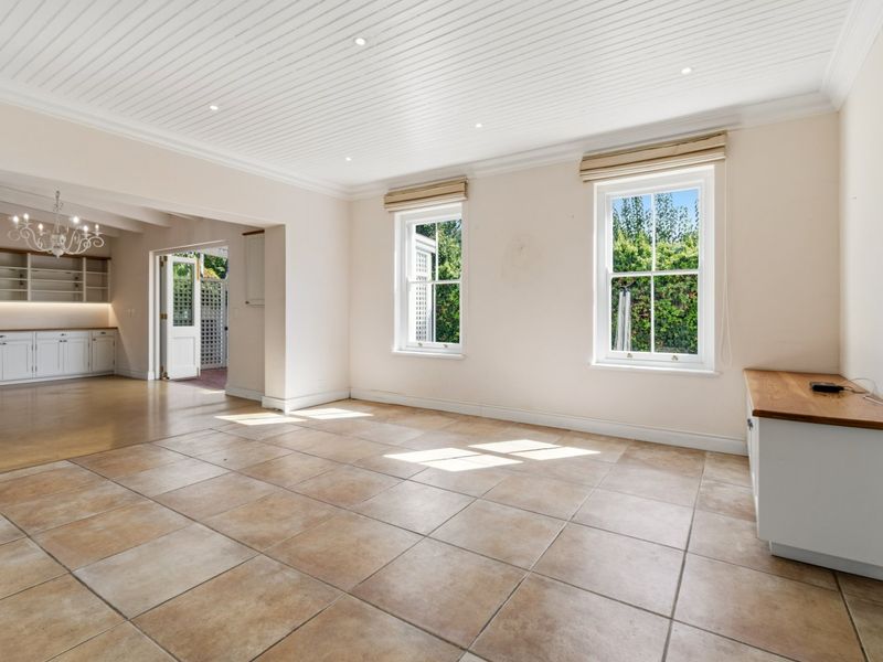 Spacious open-plan living area featuring tiled floors, tongue and groove ceiling, recessed lighting, and built-in cabinetry with timber countertops, leading to an outdoor patio.