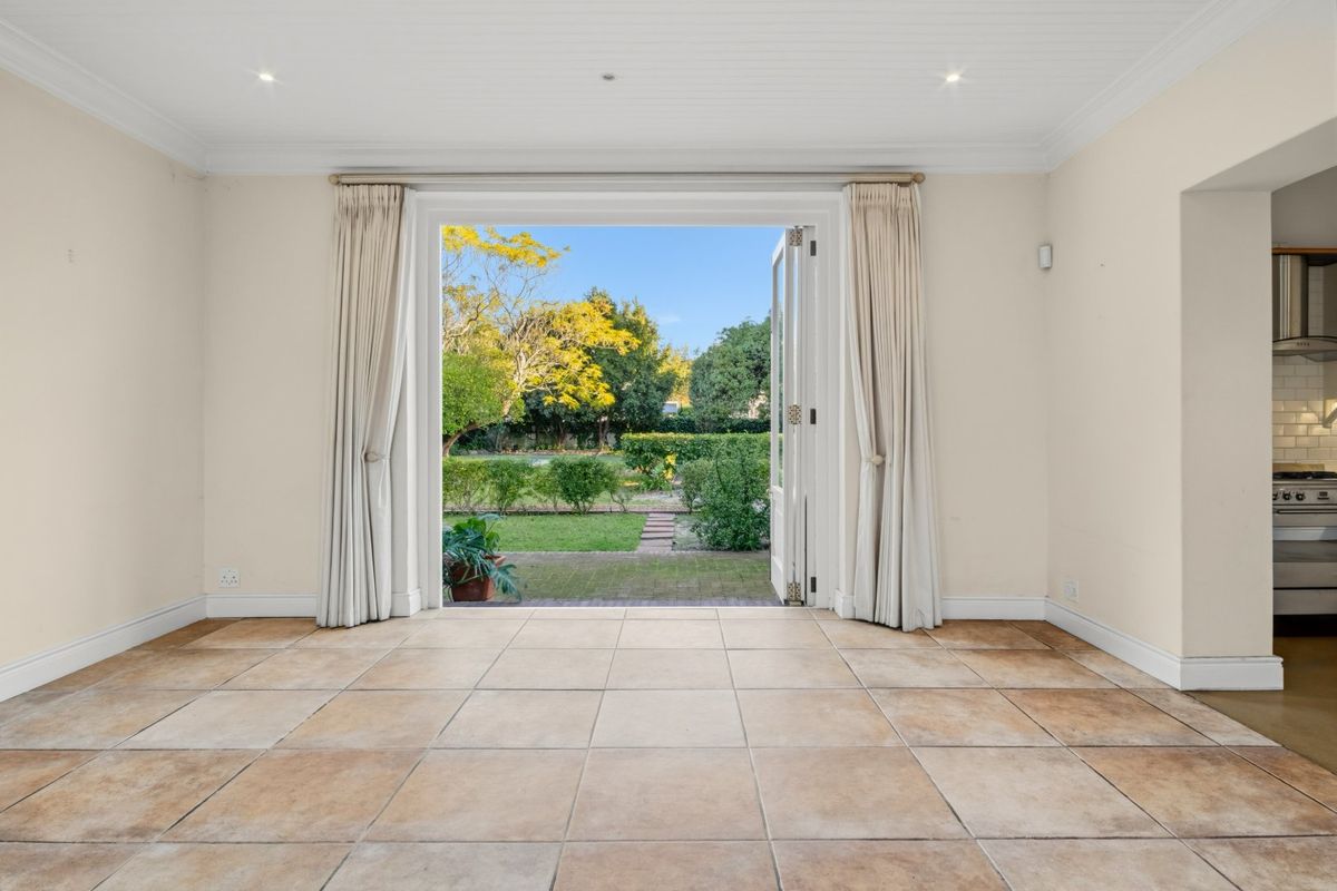 Spacious living area featuring neutral tiled flooring, recessed lighting, and large French doors opening directly onto the rear garden.