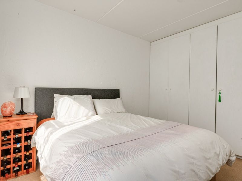 A functional bedroom featuring a built-in wardrobe with white cabinetry and neutral carpeting.