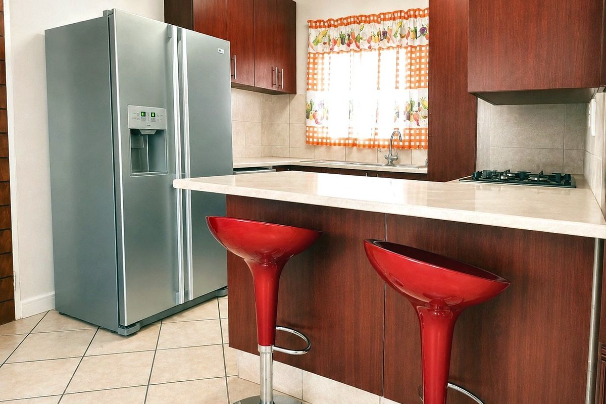 A functional kitchen featuring dark wood cabinetry, stone countertops, a breakfast bar, and a built-in gas hob with tiled flooring.
