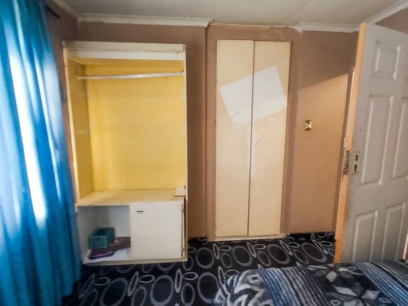 Bedroom featuring built-in cupboards and patterned flooring, requiring cosmetic updates to improve the overall aesthetic and finish.
