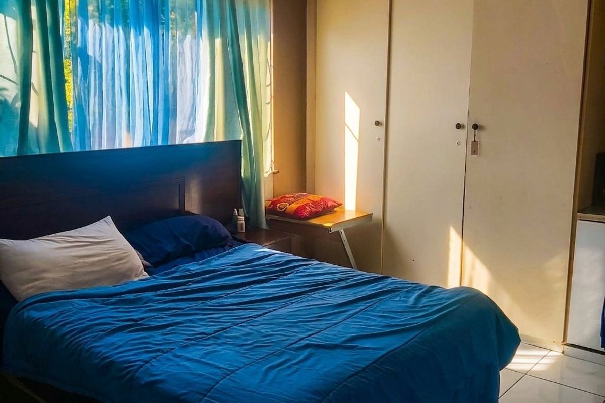 A bedroom featuring built-in cupboards and tiled flooring, benefiting from natural light through the window.