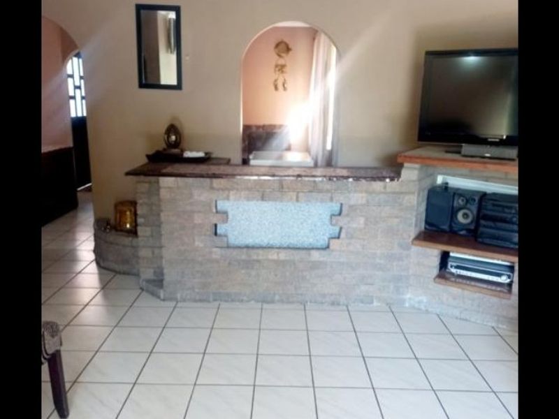 Living room featuring a brick built-in bar, tiled flooring, and an arched entryway leading to adjacent spaces.
