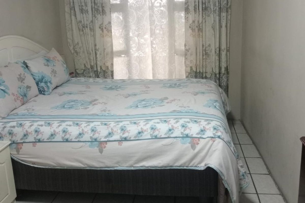 A functional bedroom featuring tiled flooring and a window with a curtain rod.