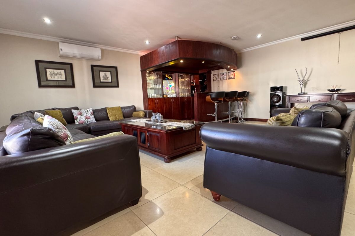 Spacious living room featuring a built-in wooden bar, tiled flooring, recessed lighting, and a wall-mounted air conditioning unit.