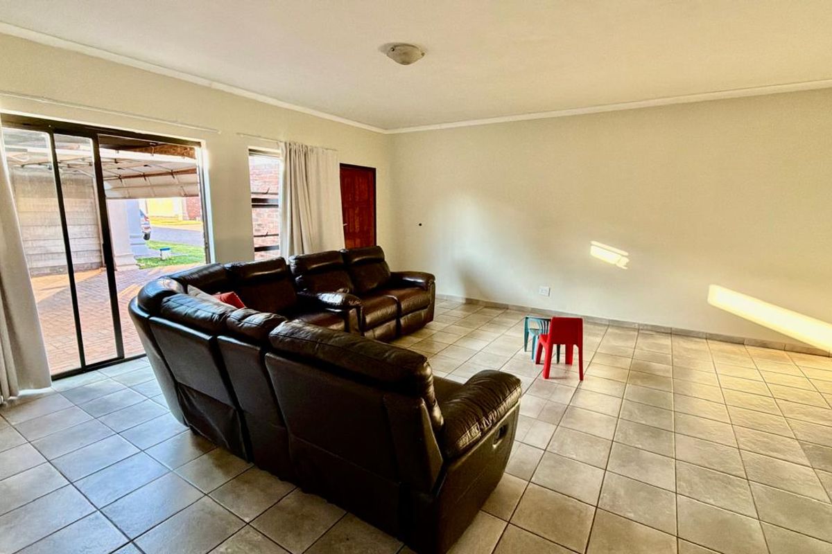 Spacious living room featuring neutral tiled flooring and a large sliding glass door providing access to the exterior.