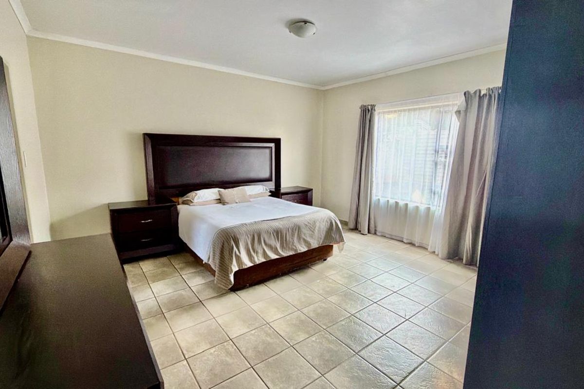 A spacious bedroom featuring neutral wall tones and durable tiled flooring, providing a clean and functional living space.