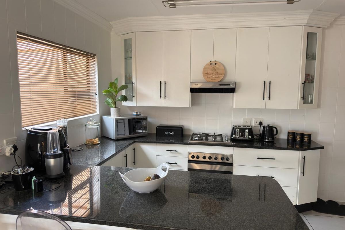 A well-maintained kitchen featuring white cabinetry, dark granite countertops, a gas hob, and a built-in oven with a tiled backsplash.