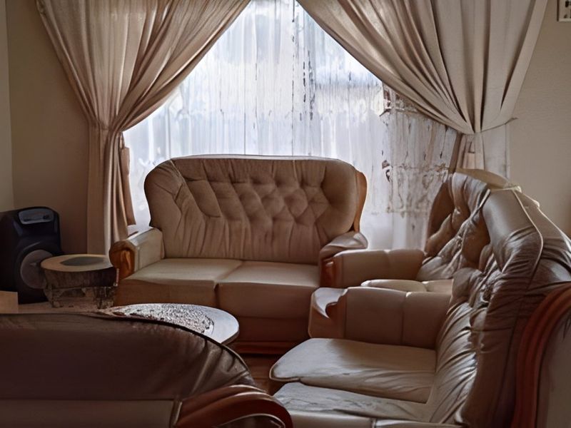 A living room area featuring a large window with curtains, providing natural light to the space.