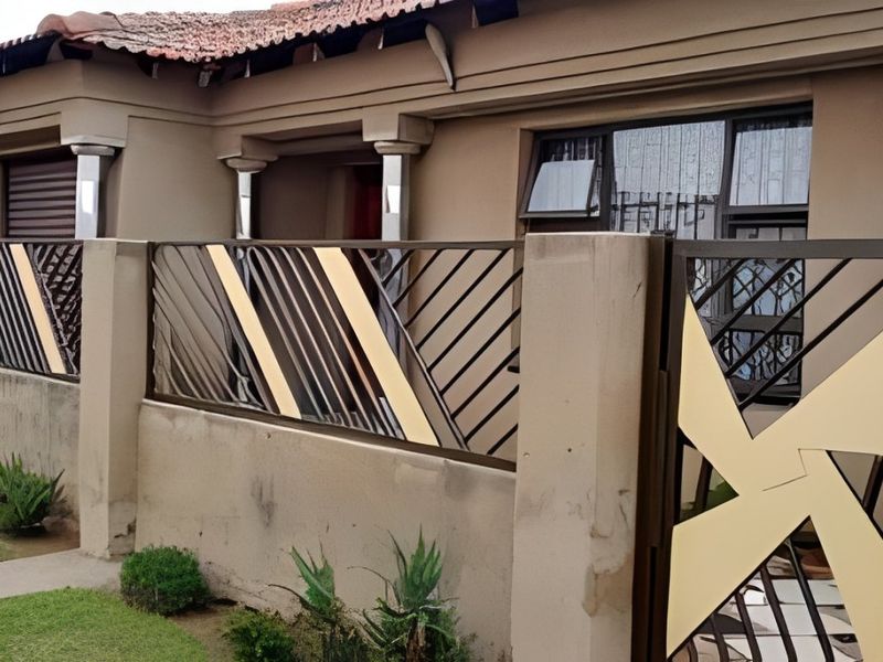 Front view of the property featuring a decorative metal security gate, perimeter wall, and aluminium window frames under a tiled roof.