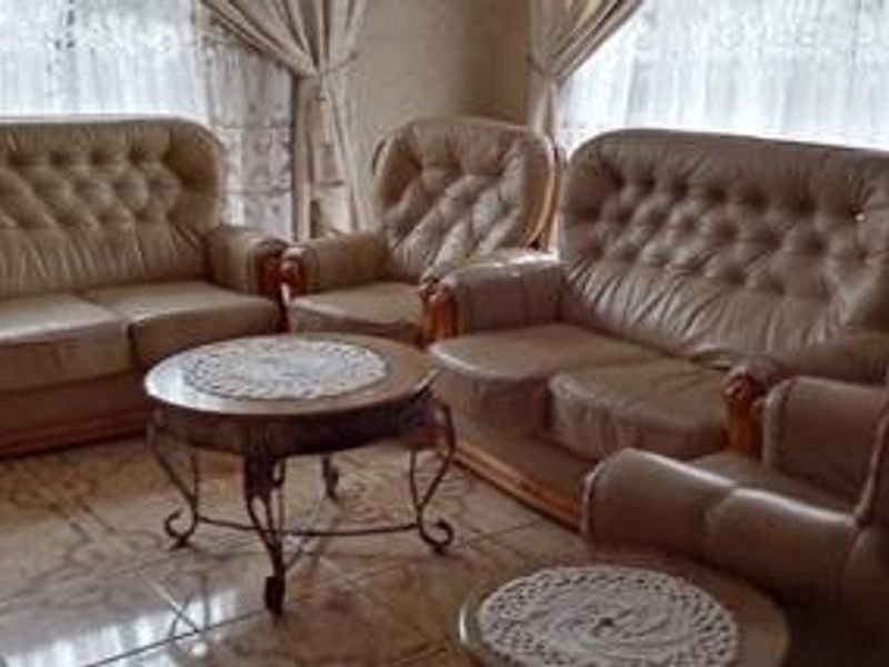 A living room area featuring tiled flooring and natural light from window treatments.