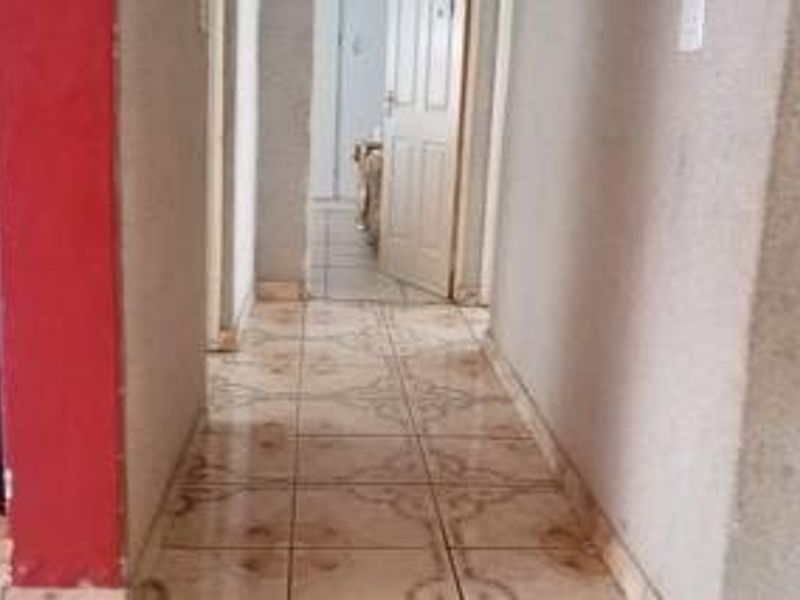 A narrow interior hallway featuring tiled flooring and access to adjacent rooms through standard internal doors.
