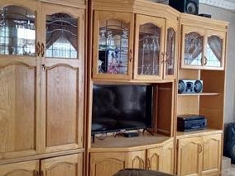 A living room featuring extensive built-in wooden cabinetry with glass-fronted display sections and decorative crown molding.