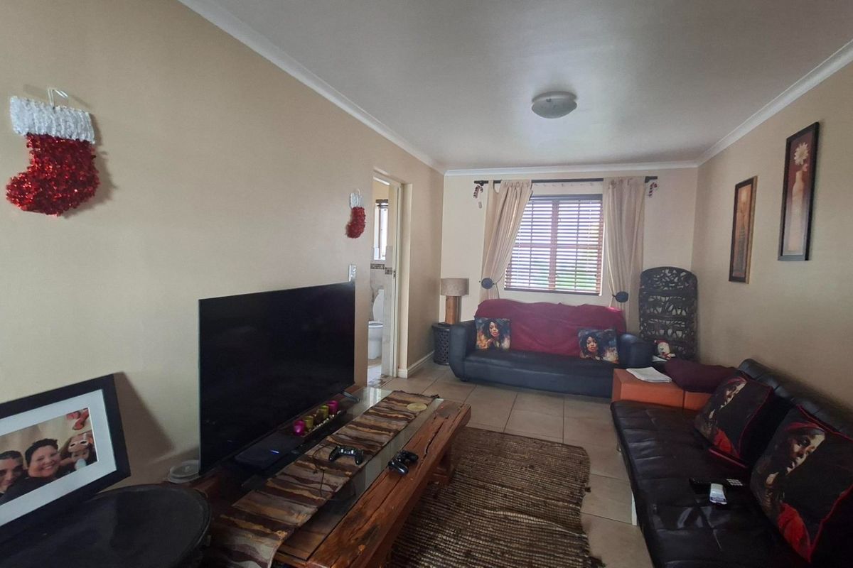 A comfortable living room featuring tiled flooring, coved ceilings, and a window with fitted blinds, providing a functional and inviting space.