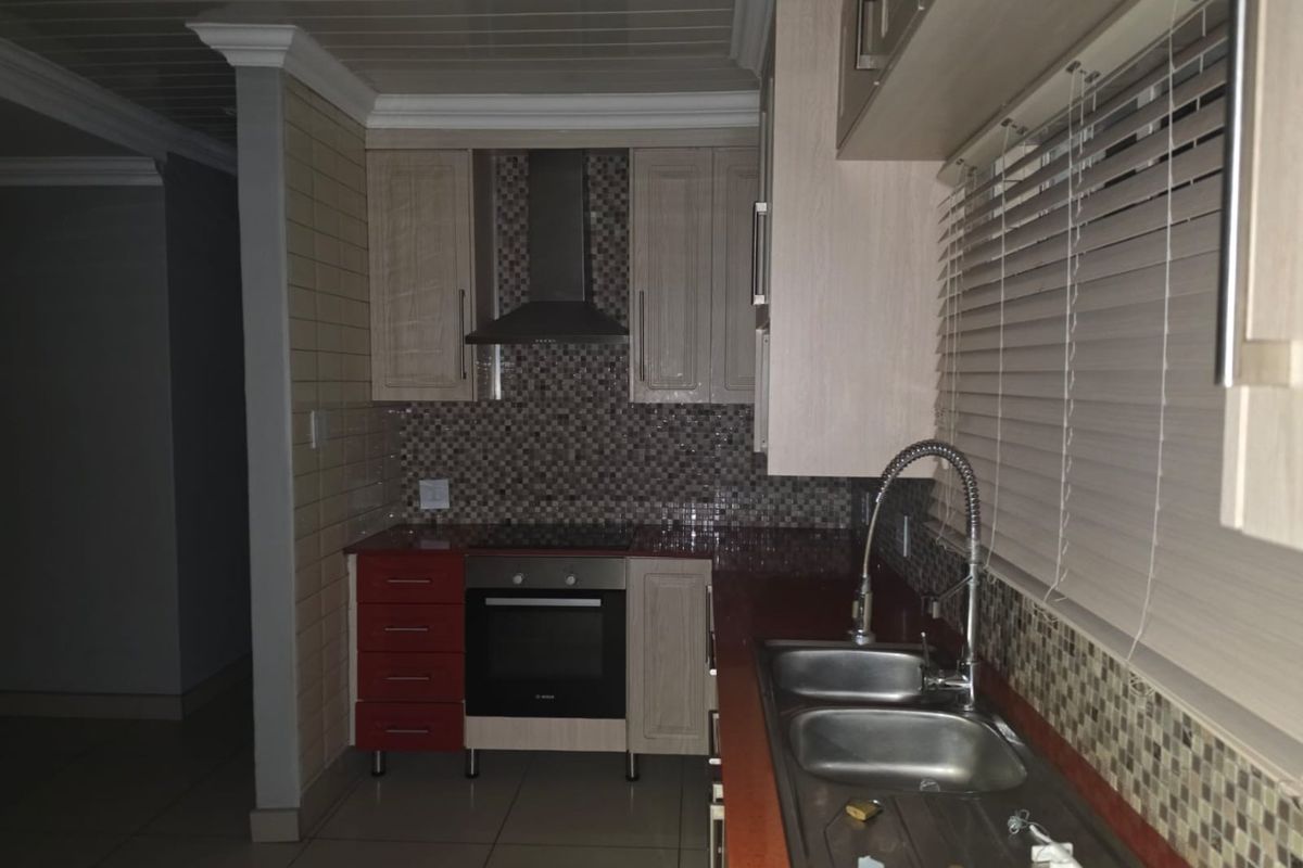 A functional kitchen featuring built-in cabinetry, a mosaic tile backsplash, integrated oven with extractor fan, and a double basin sink with a gooseneck faucet.