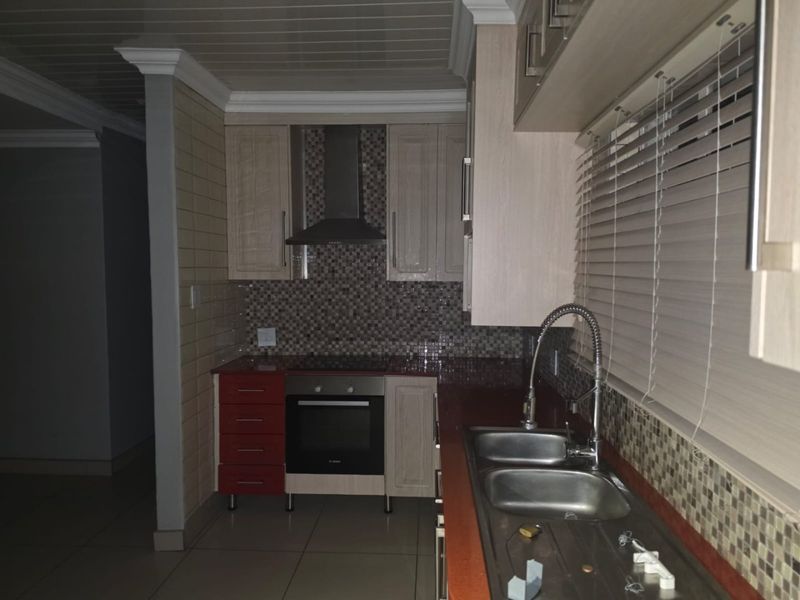 A functional kitchen featuring built-in cabinetry, a mosaic tile backsplash, integrated oven with extractor fan, and a double basin sink with a gooseneck faucet.