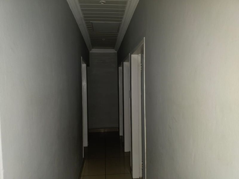 A narrow interior hallway featuring tiled flooring and a tongue and groove ceiling with an access hatch.