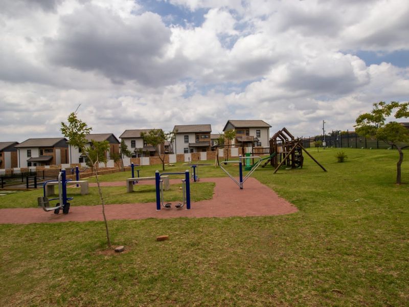 Communal outdoor recreational area featuring a playground and outdoor gym equipment set within a landscaped residential estate.