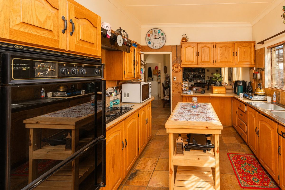 A functional kitchen featuring traditional wooden cabinetry, built-in double oven, hob, and tiled surfaces, offering a classic layout with potential for modern updates.