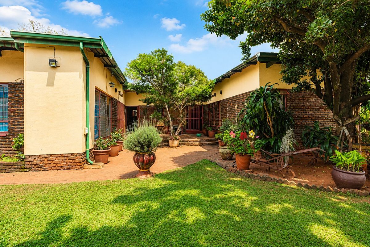 A private rear courtyard featuring a paved patio area, established garden, and brick exterior walls, providing a peaceful outdoor space.
