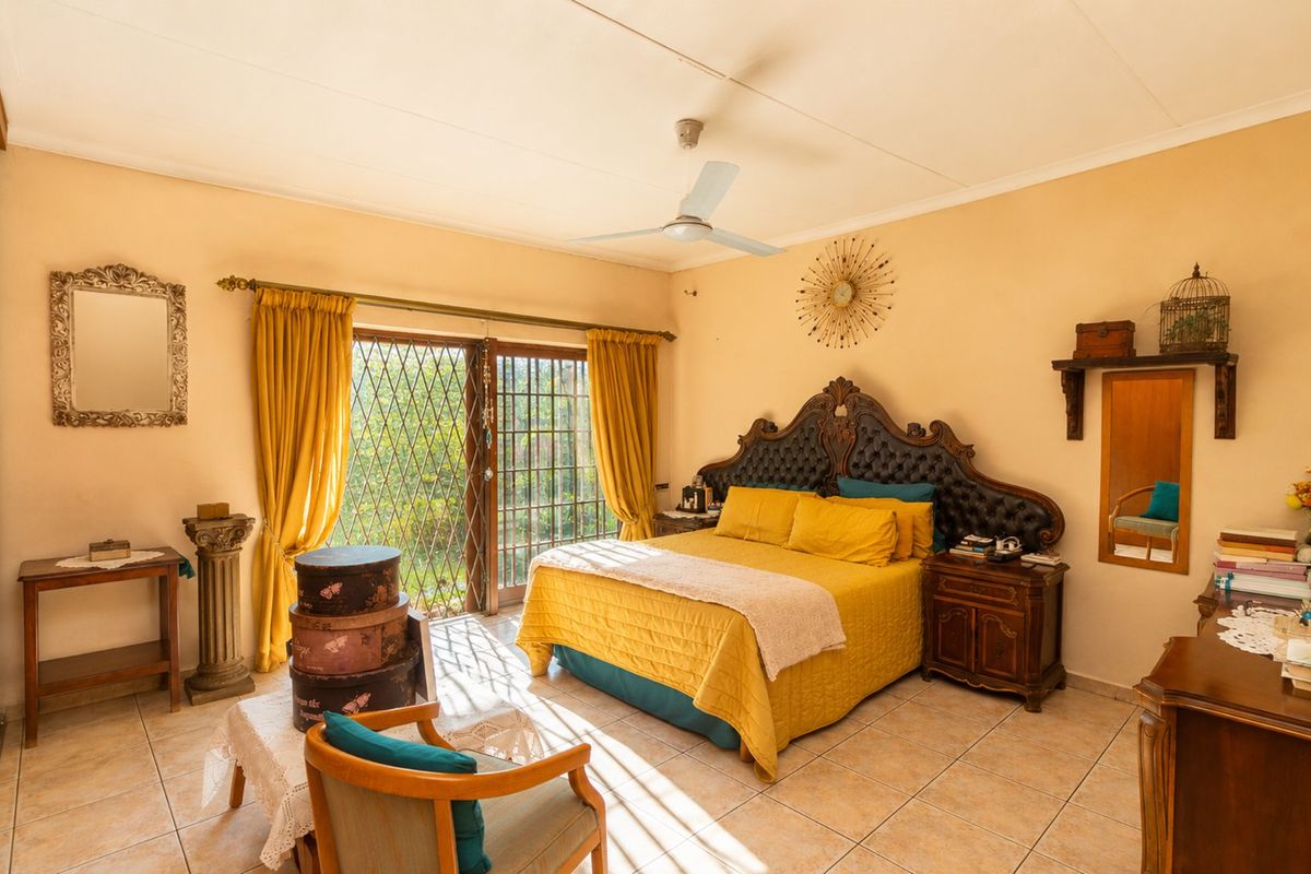 Spacious bedroom featuring tiled flooring, a ceiling fan, and sliding glass doors with security gates providing access to the outdoors.
