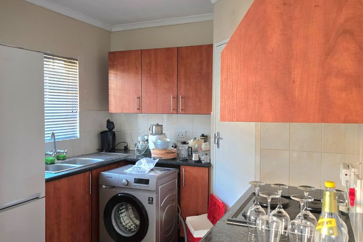 A functional kitchen featuring laminate cabinetry, granite countertops, a built-in hob, and tiled backsplash, offering a practical layout for daily meal preparation.