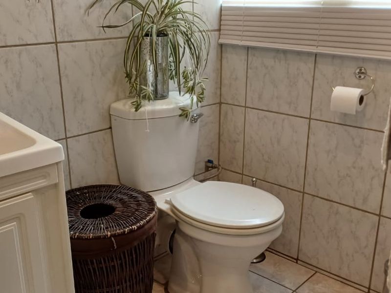 A functional bathroom featuring a vanity cabinet with a basin, a standard toilet, and tiled wall and floor finishes.
