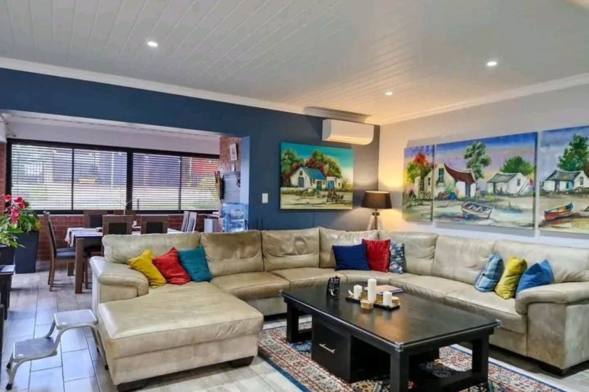 Spacious open-plan living area featuring modern timber-look tiles, a tongue and groove ceiling, recessed lighting, and a split-system air conditioner.