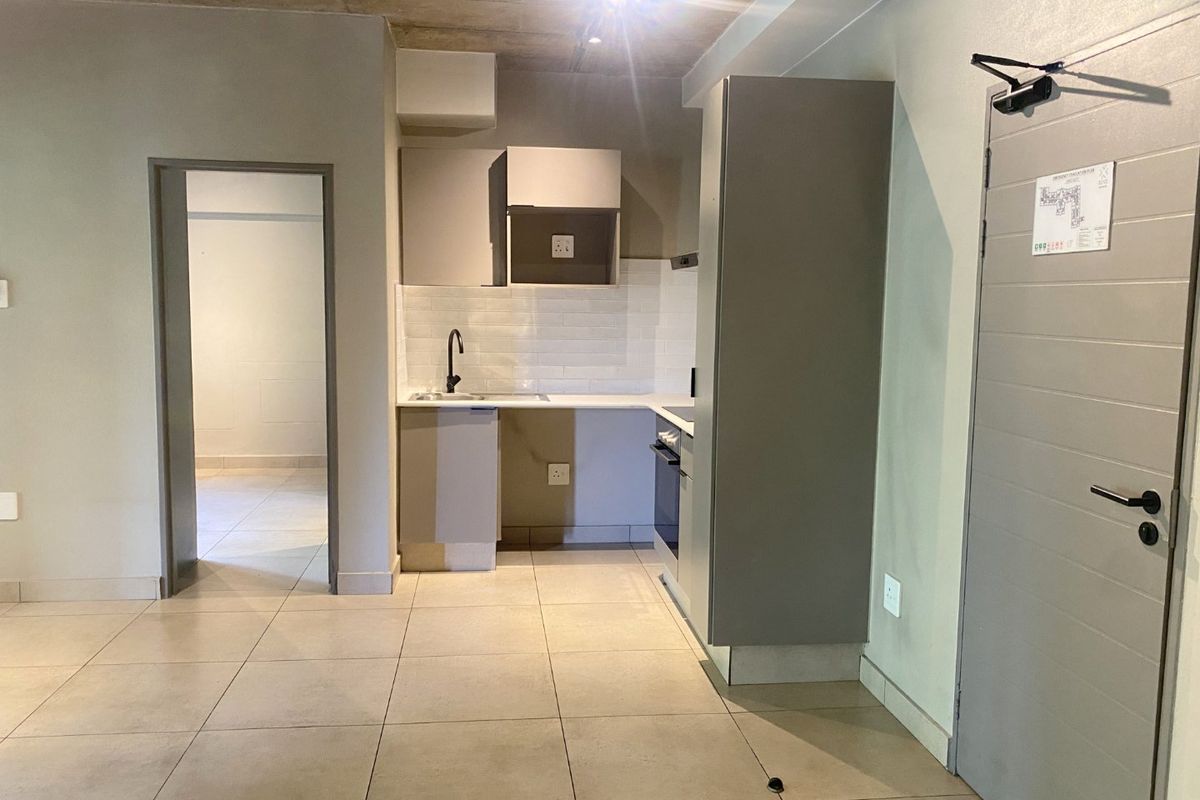 Modern kitchen featuring built-in cabinetry, subway tile backsplash, integrated oven, and sleek tiled flooring, set against an industrial-style exposed concrete ceiling.