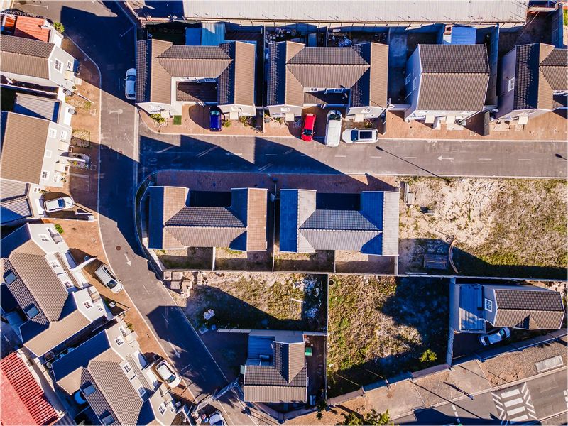 An aerial view of a residential estate showing multiple detached houses with tiled roofs, paved driveways, and surrounding street infrastructure.